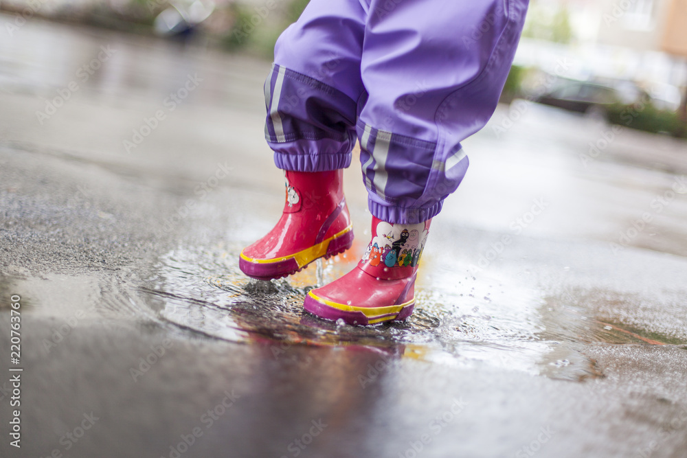 Kleines Kind steht mit Gummistiefeln in Regen / Pfütze. Little child  standing in puddle with rubber boots. Stock Photo | Adobe Stock