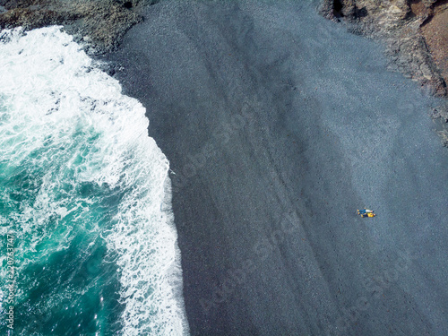 aerial view of couple lying on seashore with grey sand, djpalnssandur beach, iceland photo