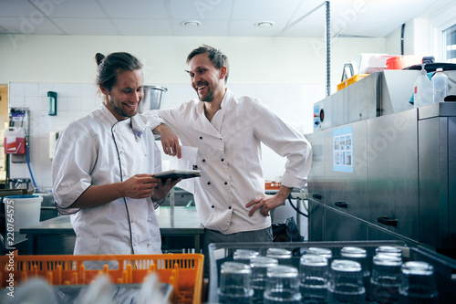 Smiling male chefs with digital tablet standing in kitchen photo