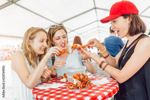 Group of young multiracial girl friends eating seafood crab or crawfish at a outdoor restaurant