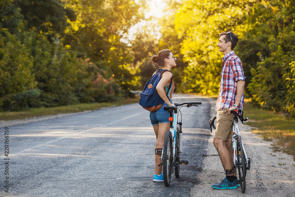 Young couple biking on a forest road in a sammer day. active recreation, sport, healthy lifestyle