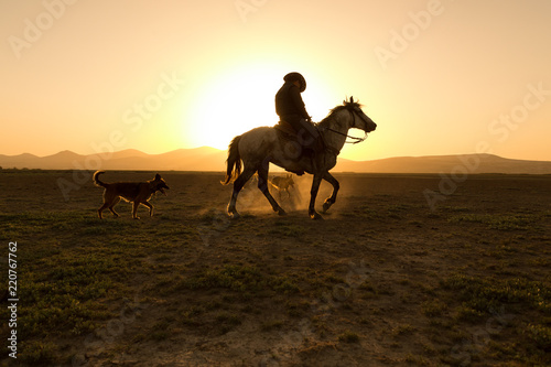 horses, cowboys, dogs at sunset