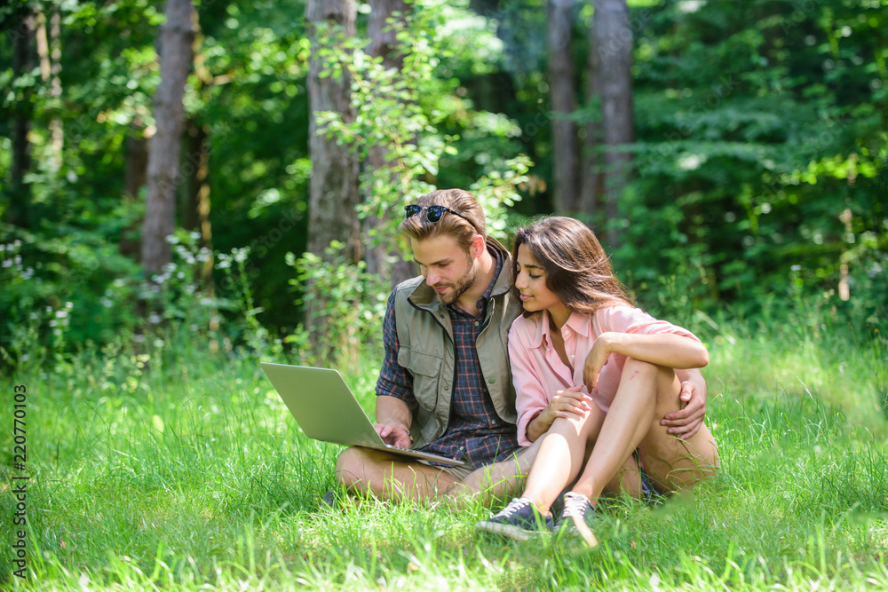 Fototapeta premium Freelance opportunity. Modern technologies give opportunity to work in any environment conditions. Couple youth spend leisure outdoors with laptop. Man and girl working with laptop at green meadow