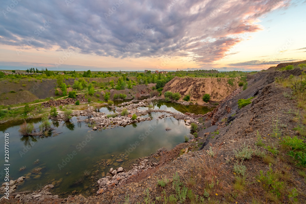 The abandoned sandstone quarry with the lake at the bottom. Evening cloudy view. Russia, Rostov-on-Don region