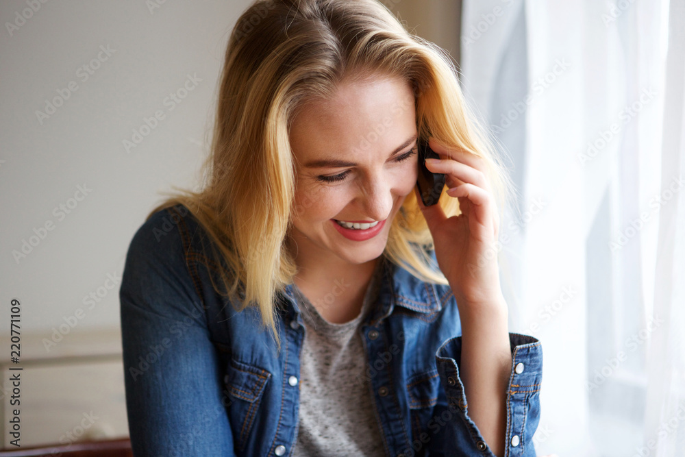 Close up young blond woman talking on cellphone by window Close up young blond woman talking on cellphone by window