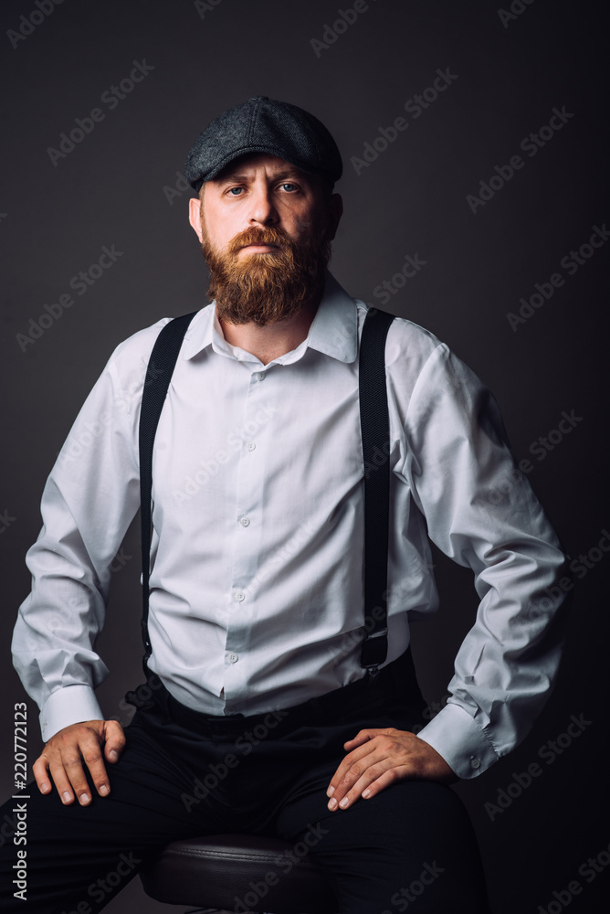 Bearded man in hat and suspenders on the black background Bearded man in hat and suspenders on the black background