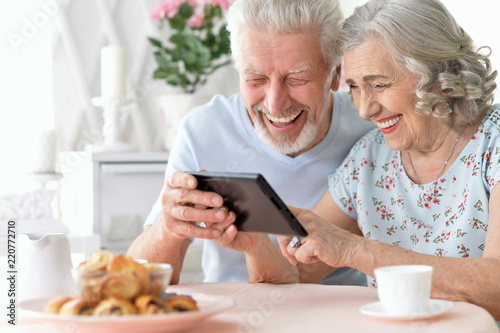happy beautiful senior couple using tablet at home