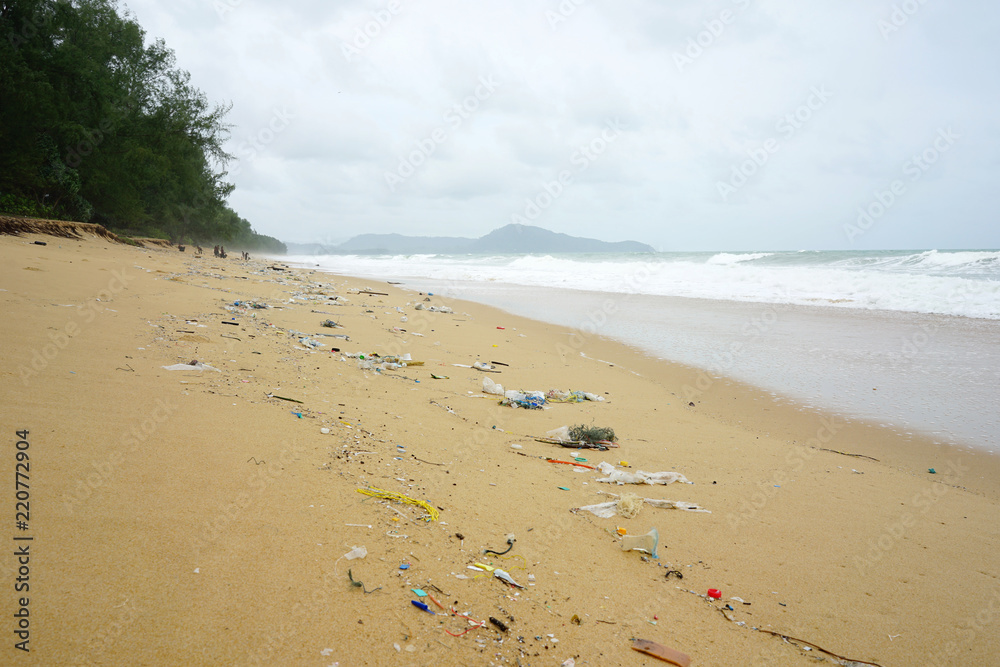 Plastic trash all over the beach with heavy wave and pine tree background Plastic trash all over the beach with heavy wave and pine tree background