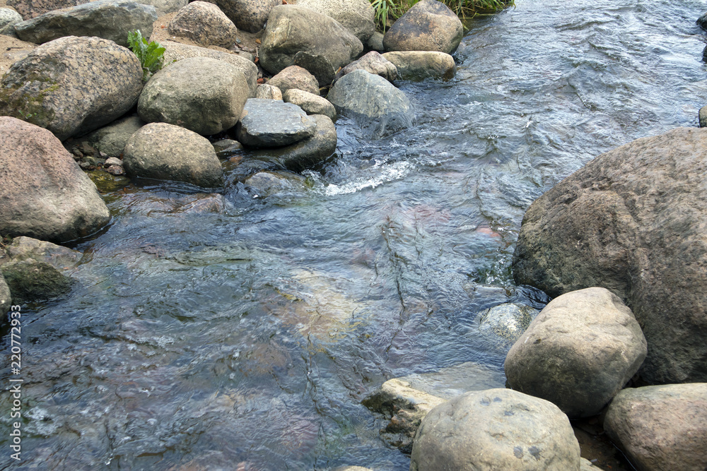 Small creek with stony bottom, rapid stream running between boulders Small creek with stony bottom, rapid stream running between boulders
