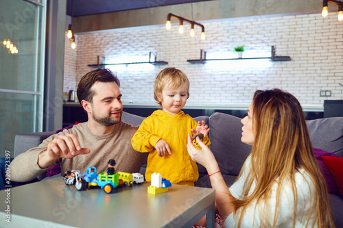 Wallpaper Mural Mother, father and son play developing games indoors. A happy family is playing at the table in the room. Torontodigital.ca