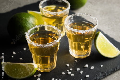 Macro photo of shots of gold Mexican tequila with lime and salt on wooden rustic background. Alcoholic drink concept. selective focus.