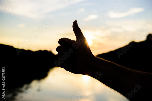 Sunset sunlight romantic atmosphere. Thumbs up gesture sign of best choice approve and accept. Top places to visit in evening. Silhouette thumb up gesture in front of sunset above river water surface