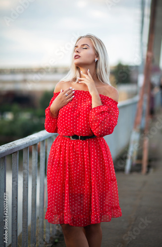 Stylish blonde girl with closed eyes posing on the bridge in the evening