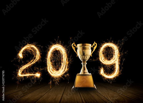 2019 written with Sparkle firework with champion golden trophy on black background.