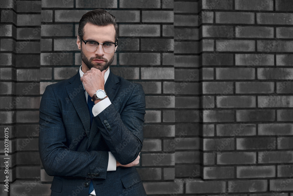 Portrait of a smiling handsome businessman with arms folded over concrete wall Portrait of a smiling handsome businessman with arms folded over concrete wall