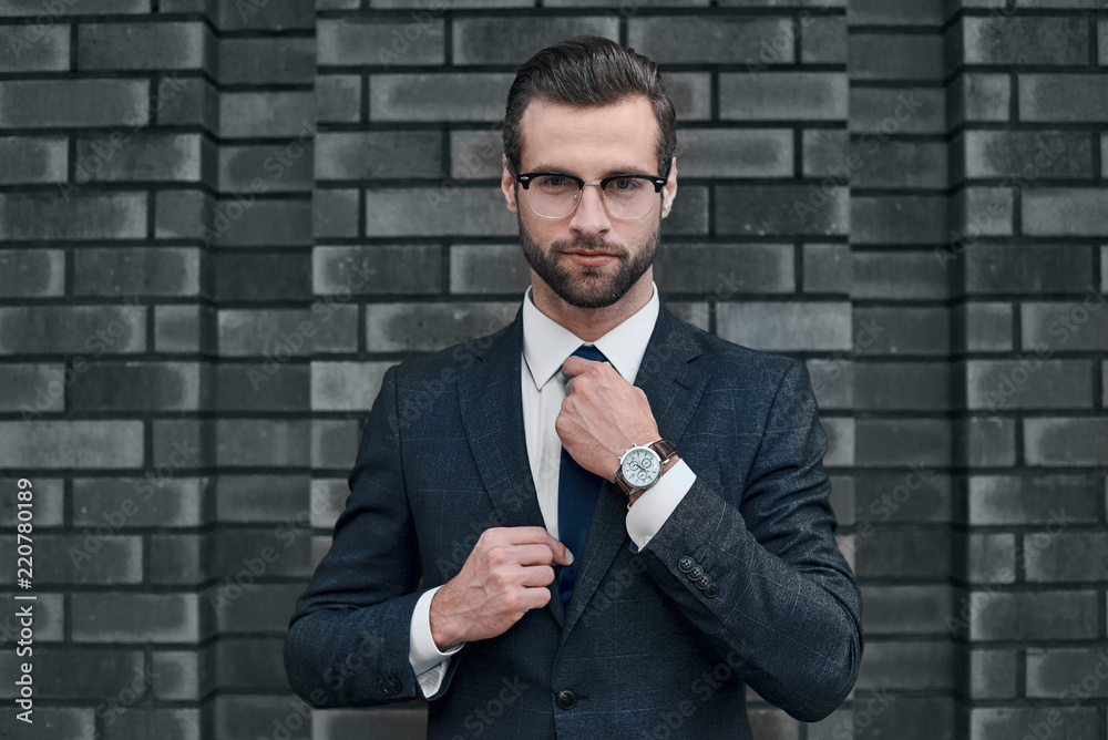 Portrait of a smiling handsome businessman with arms folded over concrete wall Portrait of a smiling handsome businessman with arms folded over concrete wall