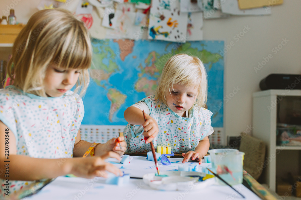 Portrait of happy adorable little girls painting at home together. Portrait of happy adorable little girls painting at home together.
