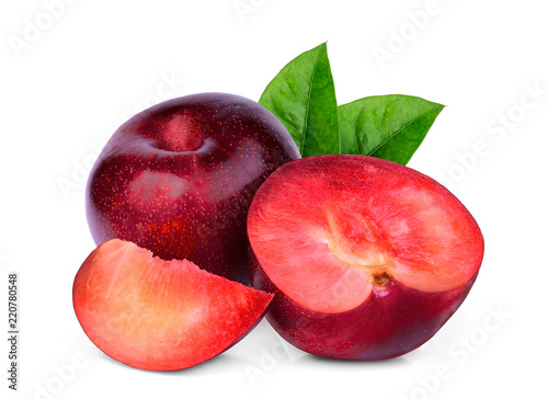whole and slices red plum with green leaves isolated on white background