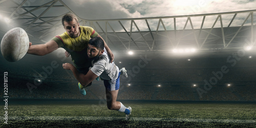Two male Rugby players fight for the ball in flight on professional rugby stadium
