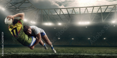 Two male Rugby players fight for the ball in flight on professional rugby stadium