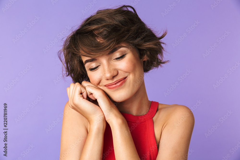 Image closeup of beautiful brunette girl 20s in casual wear smiling and holding hands at face, isolated over violet background Image closeup of beautiful brunette girl 20s in casual wear smiling and holding hands at face, isolated over violet background
