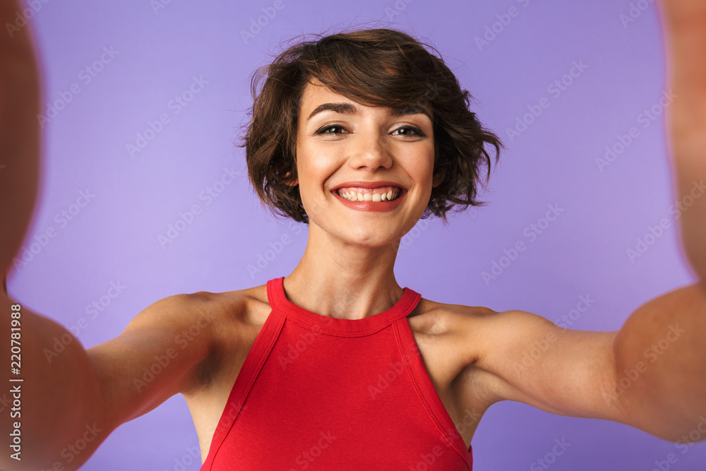 Image closeup of european charming woman 20s in casual wear smiling and taking selfie, isolated over violet background