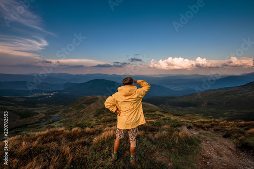 A young guy in a yellow raincoat on top of a mountain. Carpathians, Ukraine