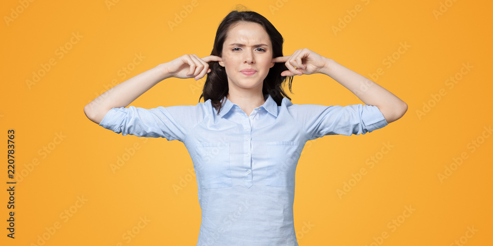 long-haired beautiful young brunette woman covering her ears with her hands long-haired beautiful young brunette woman covering her ears with her hands