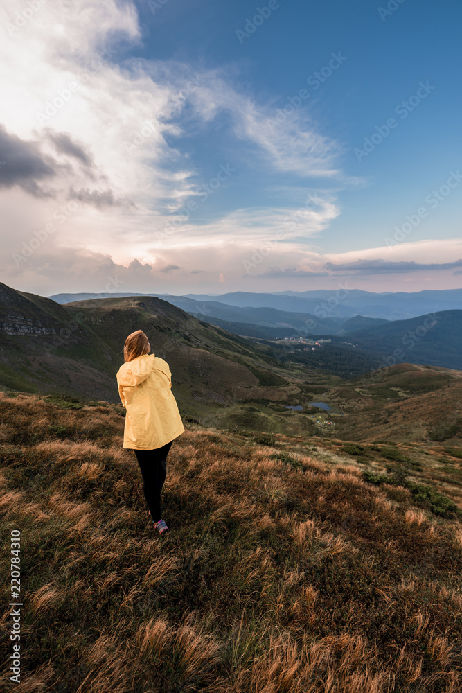 A young woman in a yellow raincoat on top of a mountain. Carpathians, Ukraine