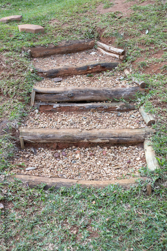 A Close up view of outside stairs made out of tree braches and stones covering the sand inbetween them