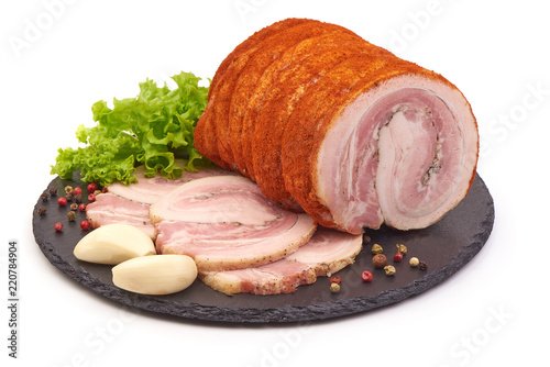 Twisted smoked pork meat with slices and spices on a shale slate plate, isolated on white background