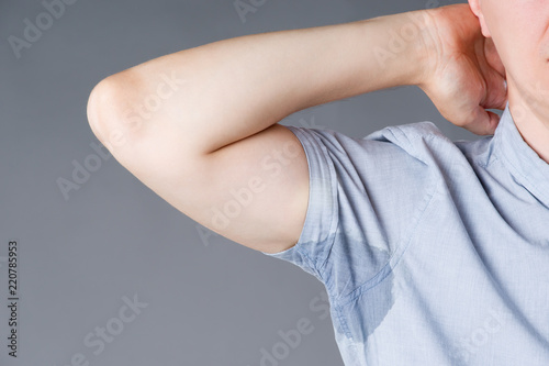 Man with sweaty armpits on gray background