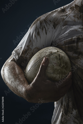 Valokuva Rugby player hands with ball on dark background. Close up