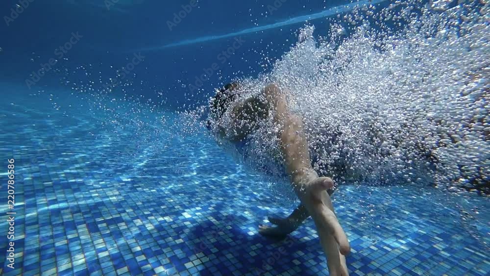 Young girl dive in blue swimming pool. Slow motion 120 FPS.