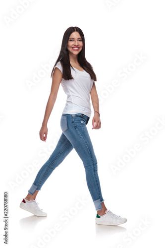 side view of cute casual womanin jeans walking
