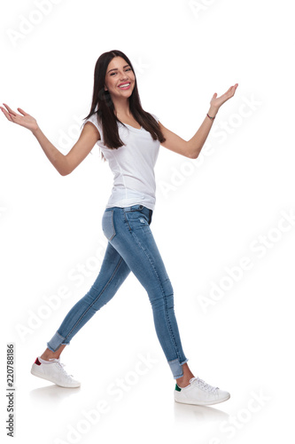 joyful woman wearing t-shirt walking to side while raising hands