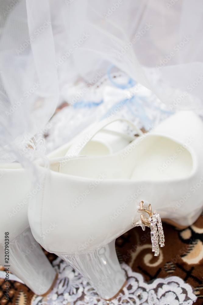 A wedding gentle bouquet of white and pink roses and high-heeled shoes on a green grass in the park. Wedding details A wedding gentle bouquet of white and pink roses and high-heeled shoes on a green grass in the park. Wedding details