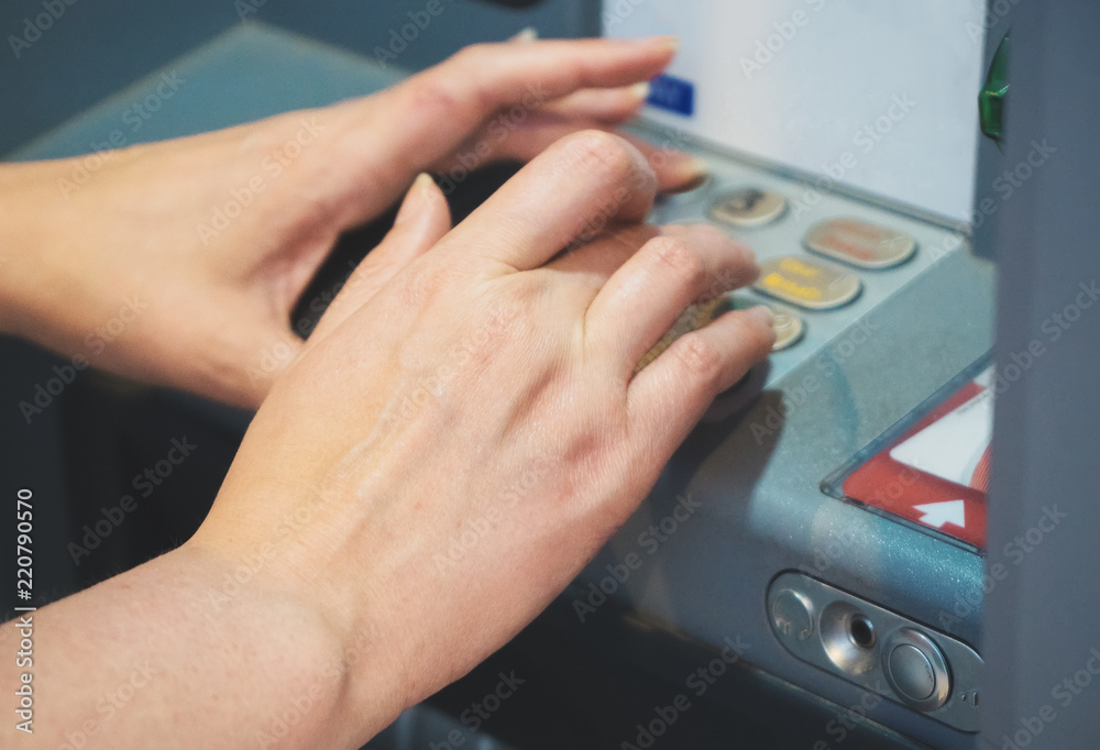 Woman using ATM on the street. Hands close-up view.