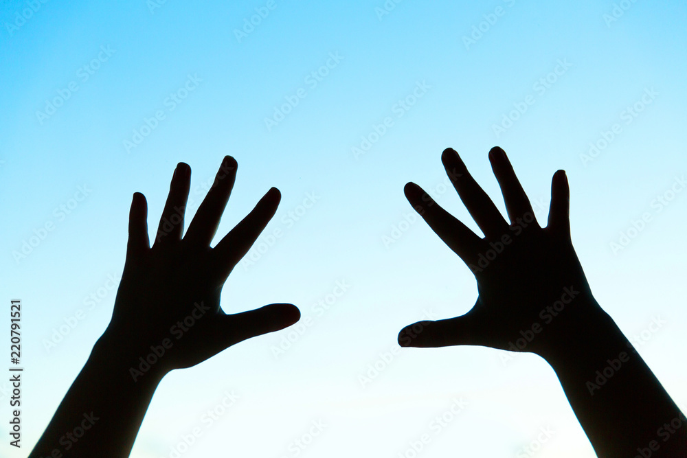 silhouette of woman's hands on blue background