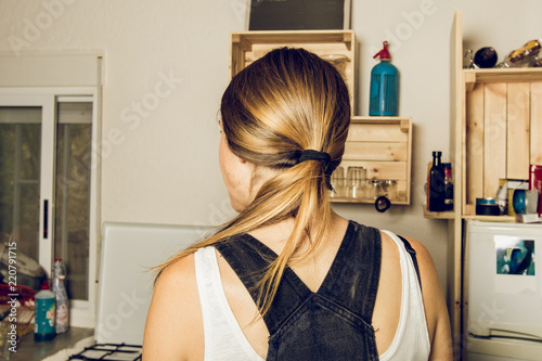 Blonde girl with her back to the kitchen. Close-up of a girl with her back to her head