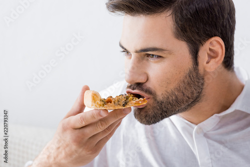 portrait of young man eating pizza alone at home © LIGHTFIELD STUDIOS
