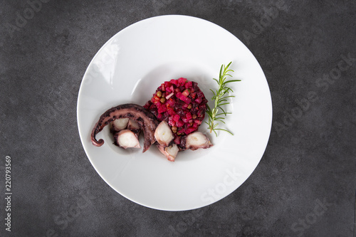 Salad from beets and octopus. Vinegret is a traditional Russian salad made from beets and vegetables. The background is gray. Top view. Copy space.
