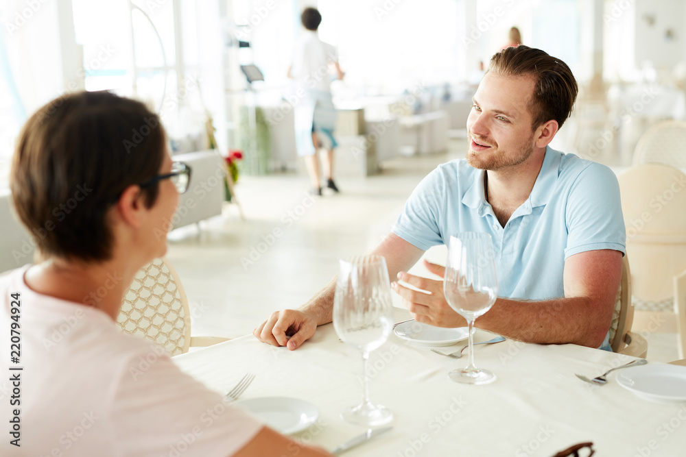 Portrait of beautiful young couple enjoying romantic dinner in restaurant sitting at table in milky white interior, copy space Portrait of beautiful young couple enjoying romantic dinner in restaurant sitting at table in milky white interior, copy space