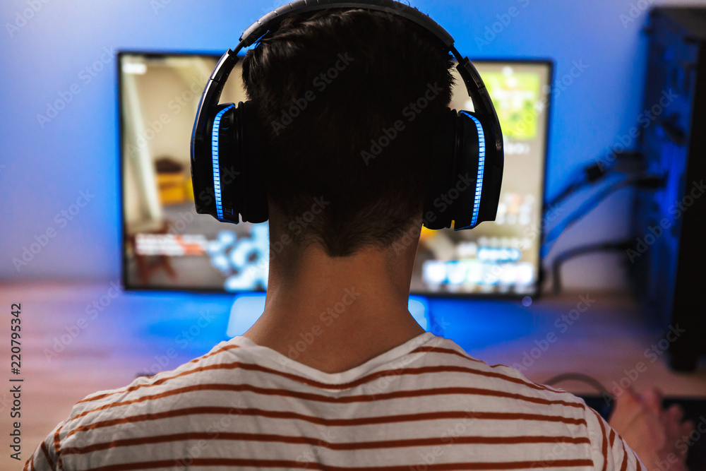 Back view of young gamer playing video games on computer Back view of young gamer playing video games on computer