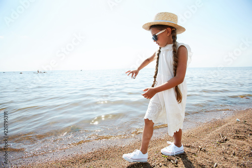 Portrait of cute girl walking along edge of water while playing on beach in Summer, copy space