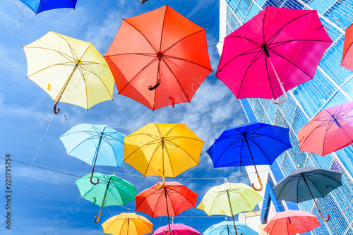 Different colorful umbrellas hanging over the street against sky