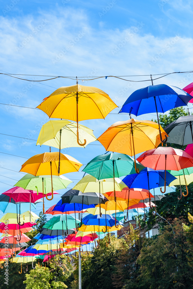 Different colorful umbrellas hanging over the street against sky