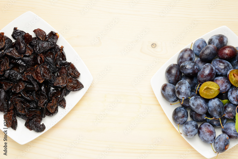 Fresh and dried plums with leaves on a wooden table background, Flat lay composition. Fresh and dried plums with leaves on a wooden table background, Flat lay composition.