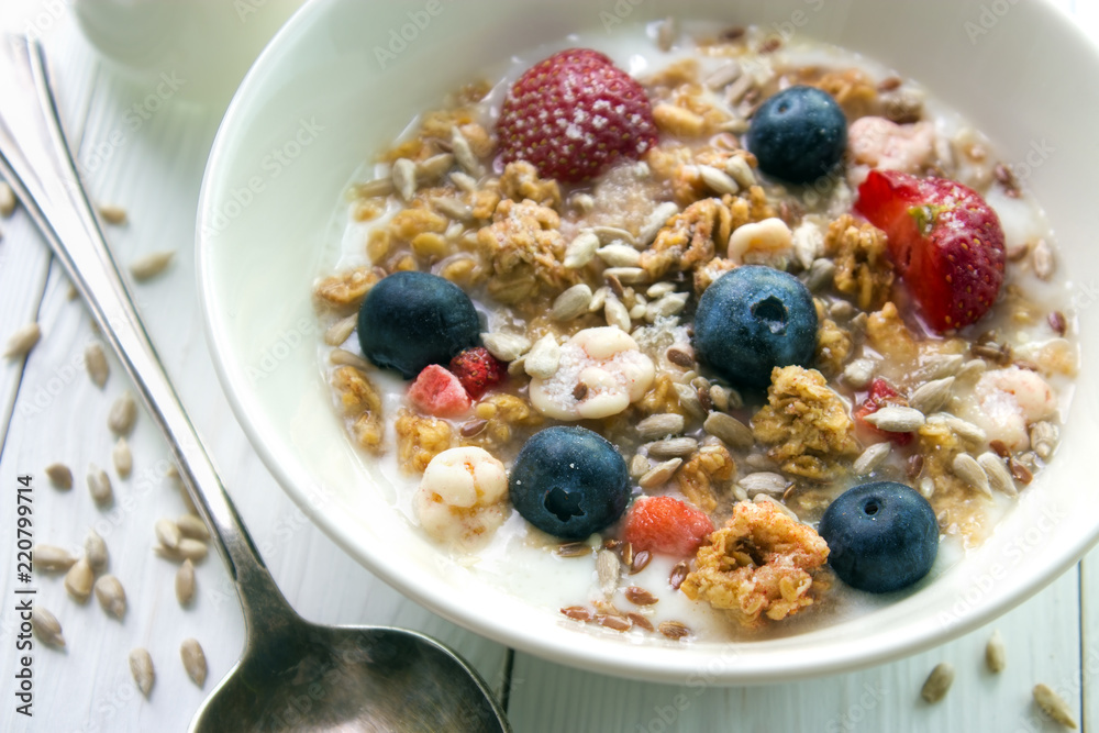 Muesli and yogurt breakfast with fresh strawberries , blueberries and seeds closeup on white wooden table Muesli and yogurt breakfast with fresh strawberries , blueberries and seeds closeup on white wooden table
