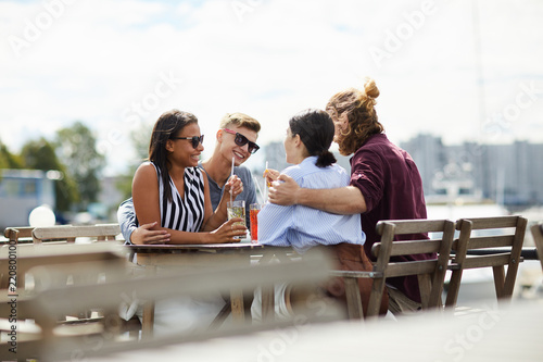 Two affectionate couples sitting in outdoor cafe, enjoying talk and drinks © pressmaster